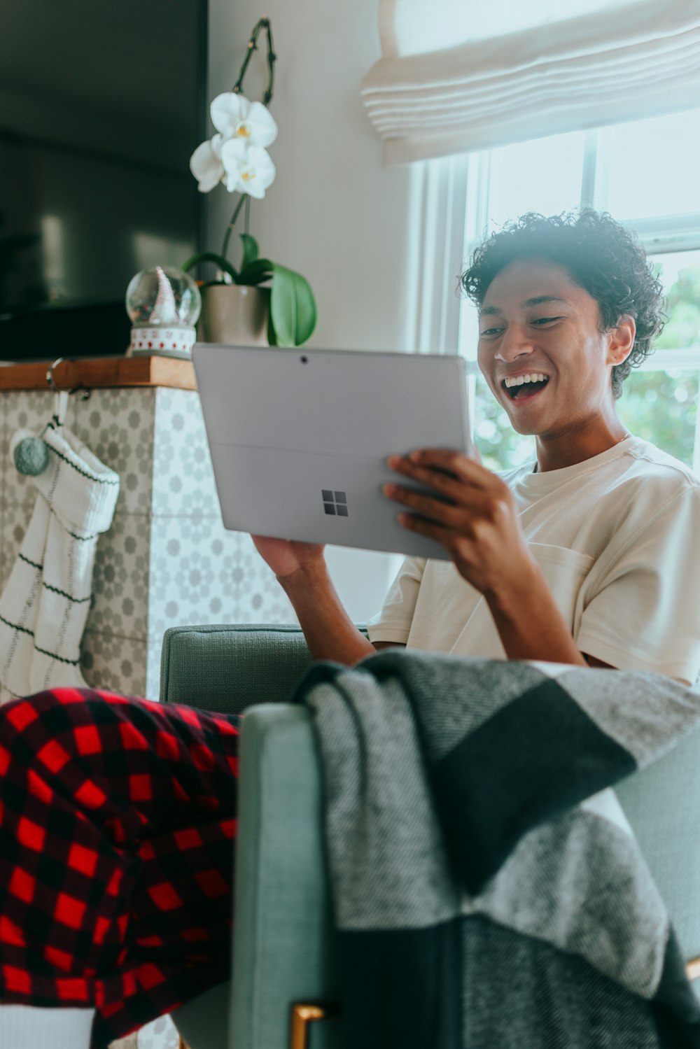 Uomo a casa che indossa pigiama sorridente allo schermo del laptop di Surface 