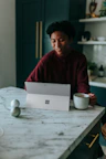 Man sitting at kitchen table watching something on his Surface laptop drinking coffee