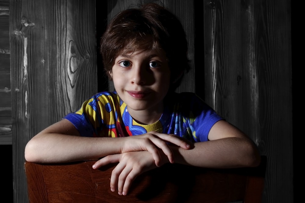 a young boy sitting in a chair with his arms crossed