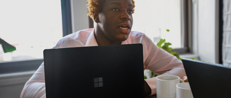 Person sitting at a desk behind a black Surface laptop