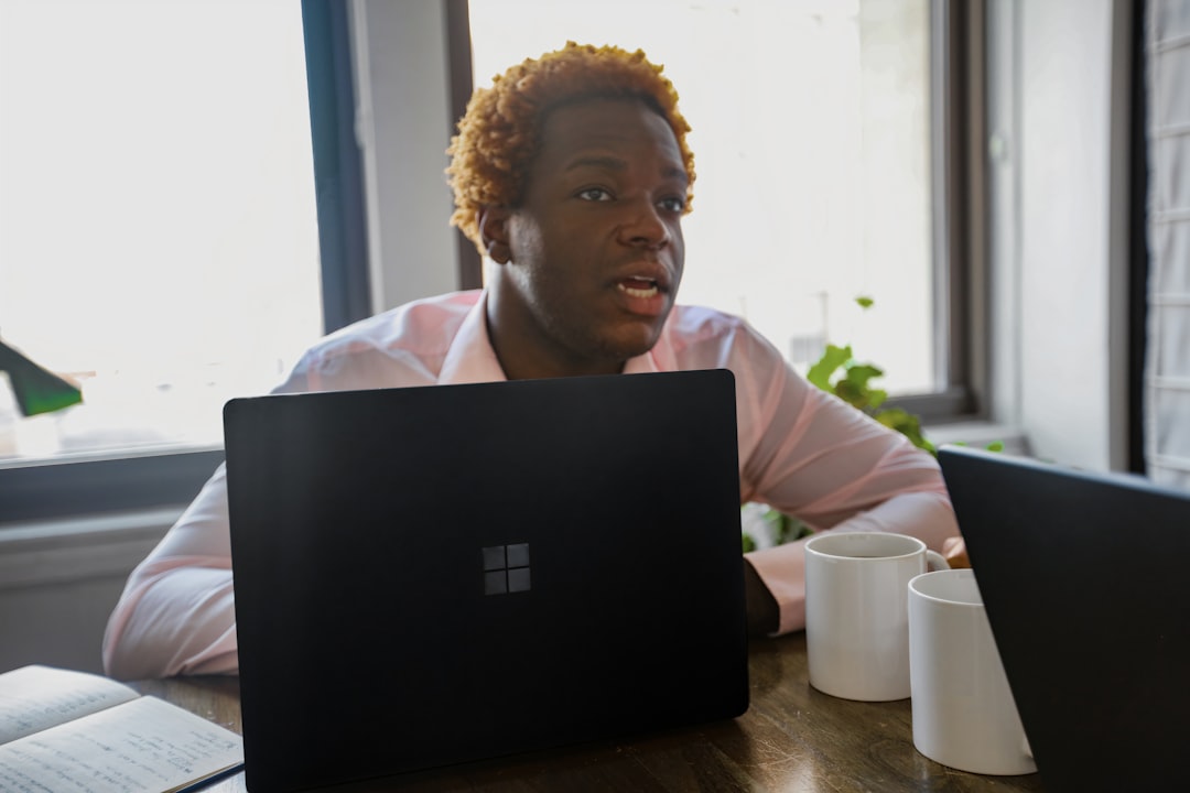 Person sitting at a desk behind a black Surface laptop