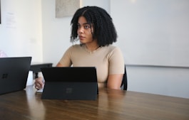 Female worker sitting in a board room with black Surface laptop on the table 