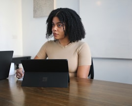 Female worker sitting in a board room with black Surface laptop on the table 