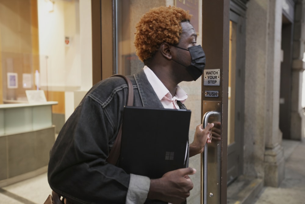 Male opening a door to leave work holding a Surface laptop