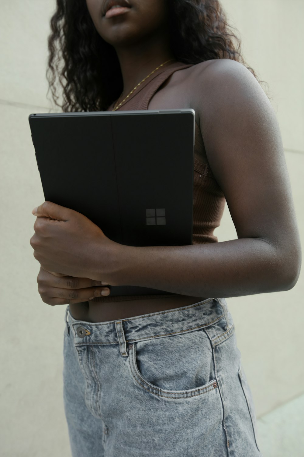 黒い Surface ノート PC を持つ女性