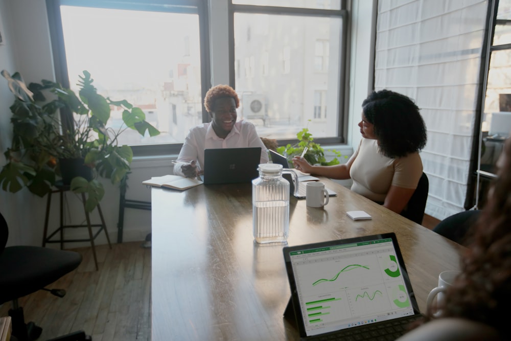 Três pessoas em uma reunião de mesa no trabalho com seu laptop Microsoft 