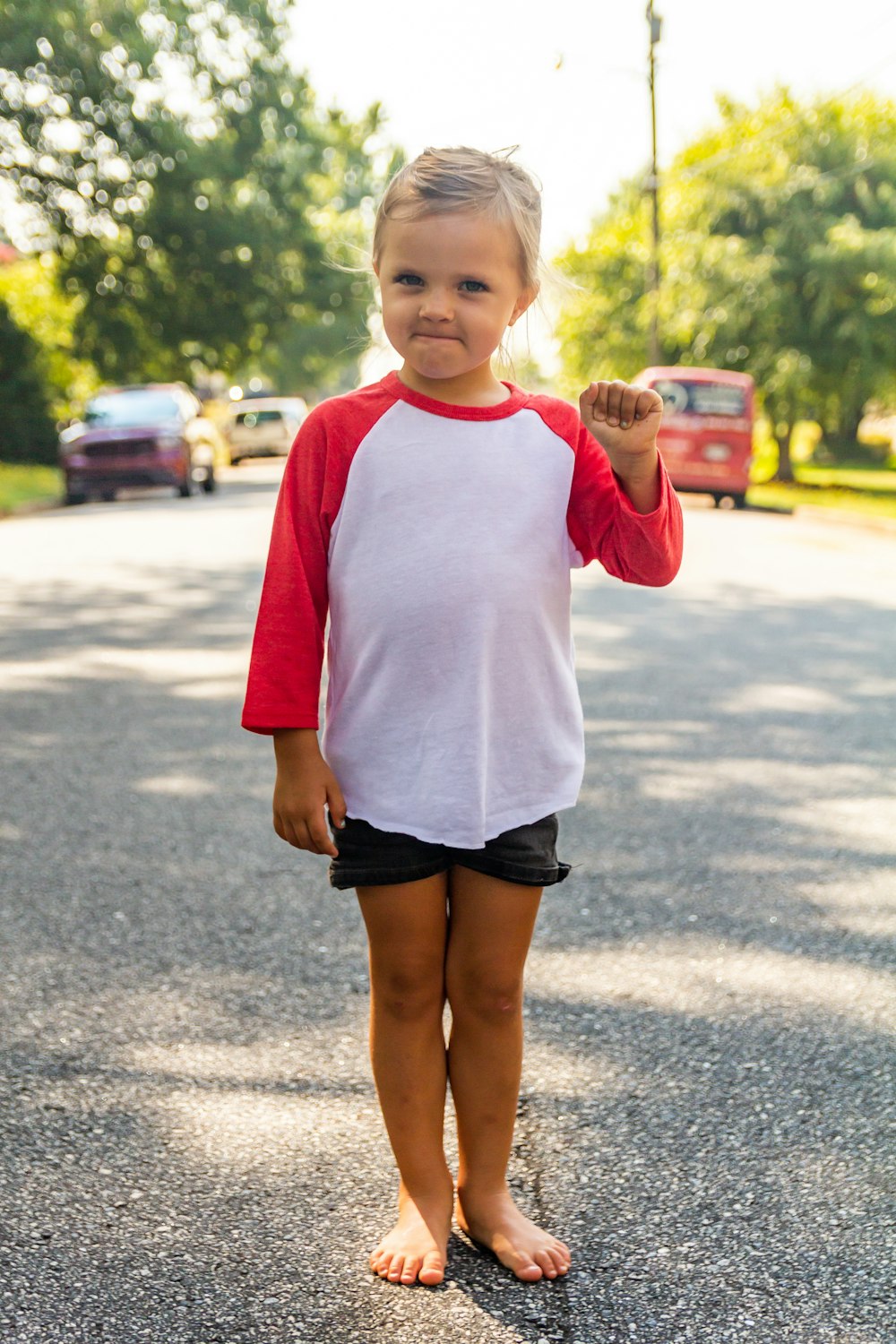 a little girl standing in the middle of the road