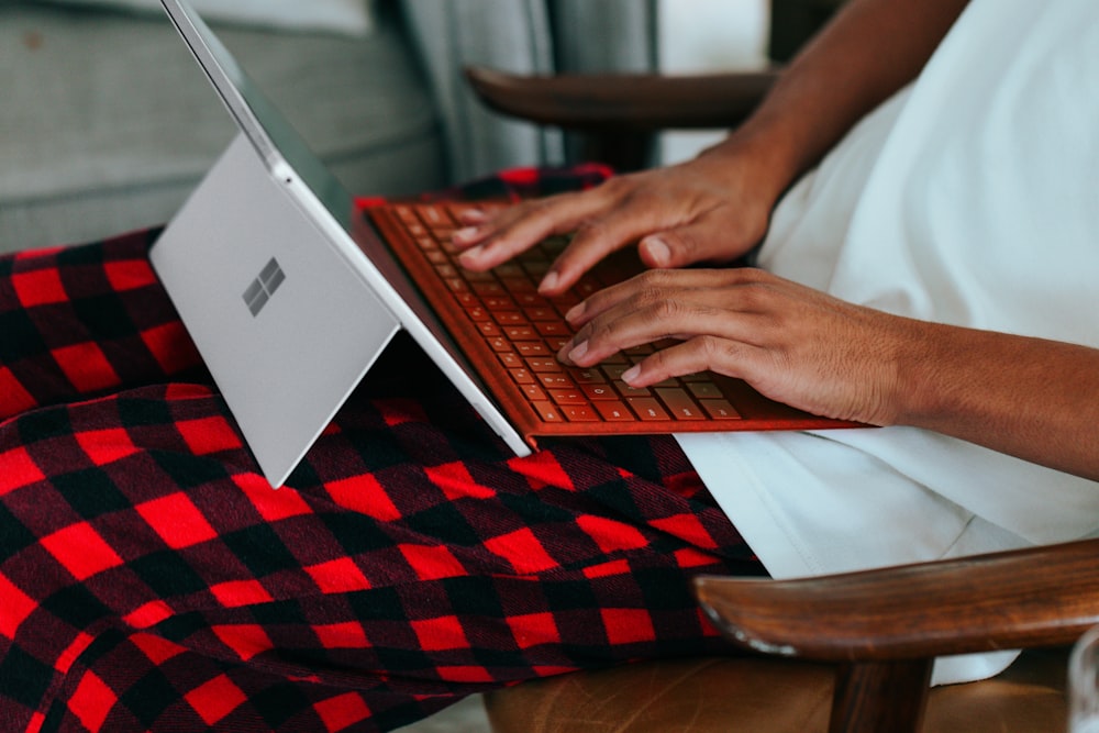 Person im karierten Schlafanzug auf ihrem Surface-Laptop zu Hause