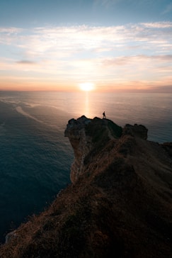 a person standing on top of a cliff overlooking the ocean