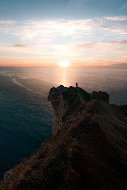 a person standing on top of a cliff overlooking the ocean