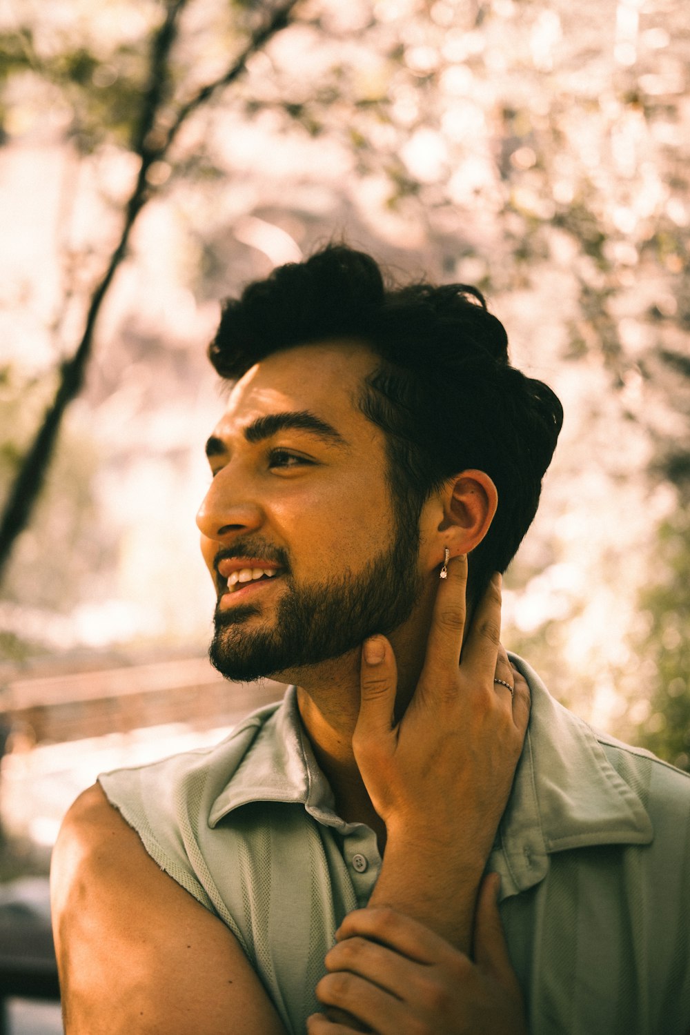 a man with a beard smiles while holding his ear