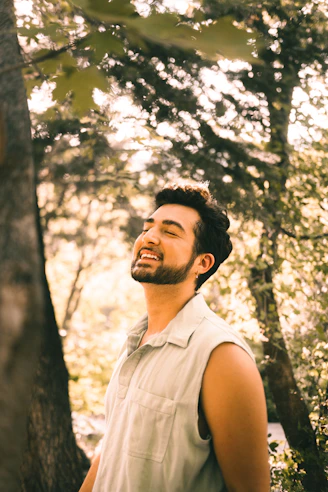 a man standing next to a tree in a forest