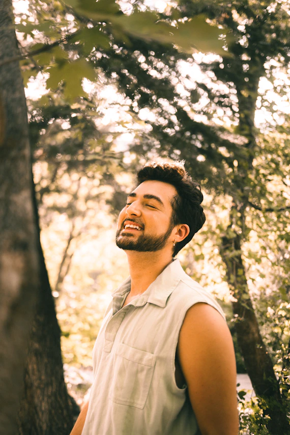 a man standing next to a tree in a forest