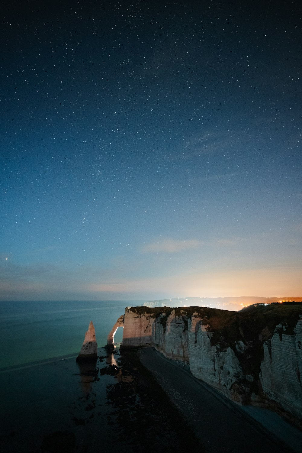 a view of the ocean at night with stars in the sky