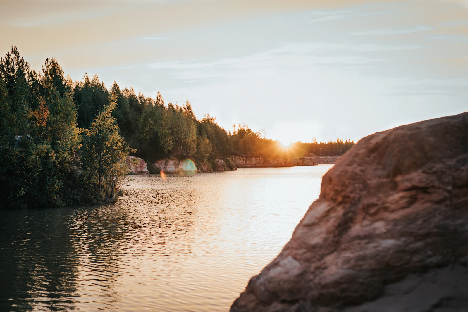 A rock face above still water at sunset, like an old flooded quarry.