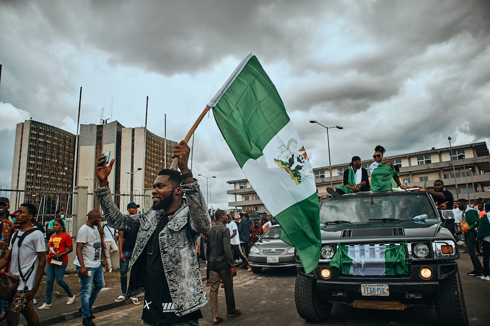 Un grupo de personas caminando por una calle con una bandera