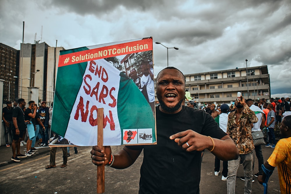 Un uomo che tiene un cartello che dice Fine SARS ora