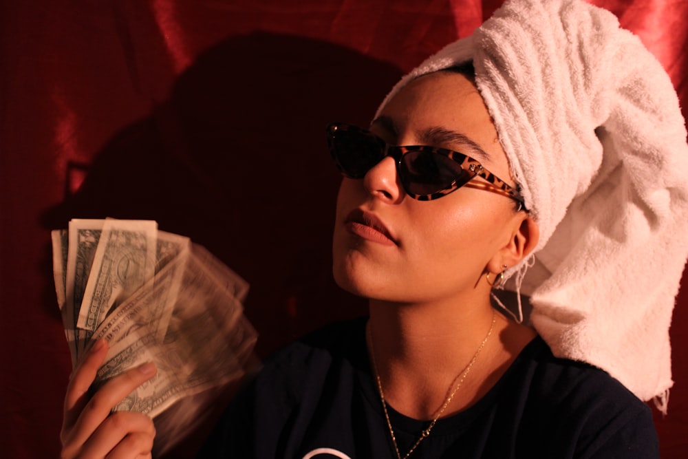 Una mujer con una toalla en la cabeza sosteniendo dinero en efectivo