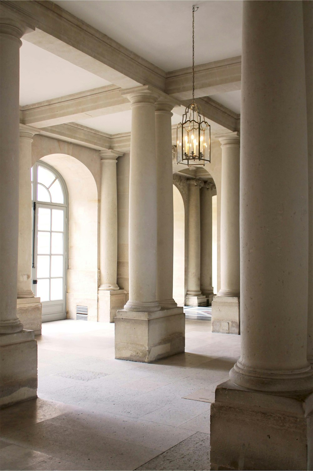 a room with columns and a chandelier hanging from the ceiling