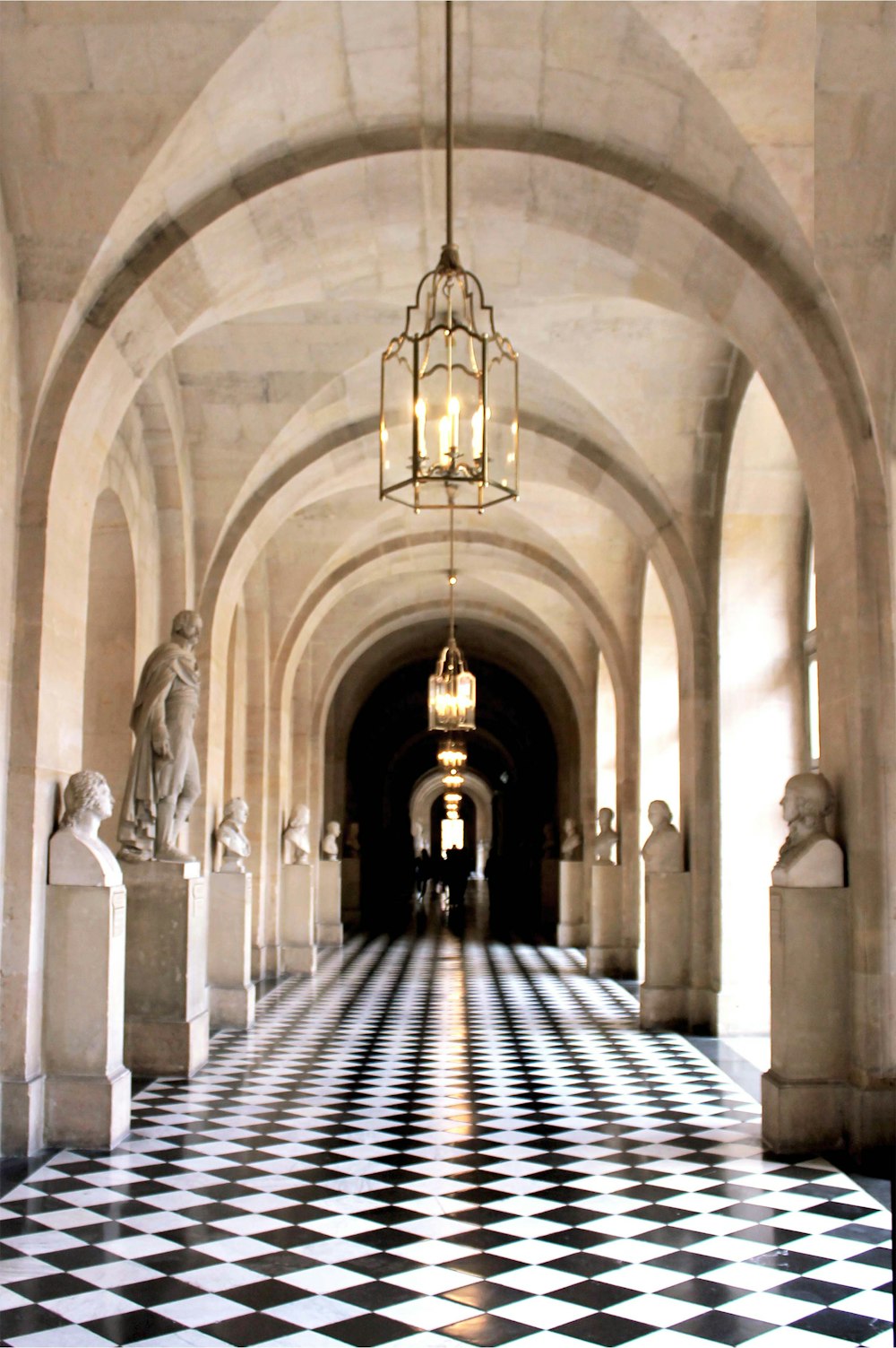 a hallway with a checkered floor and a chandelier