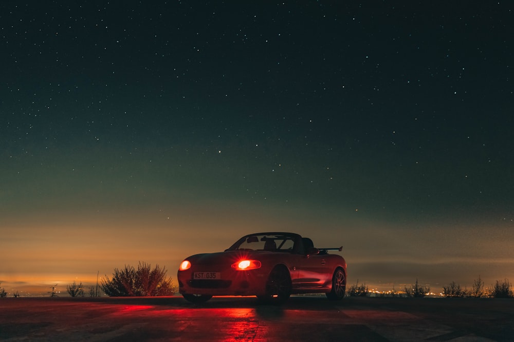 un coche aparcado al costado de la carretera por la noche