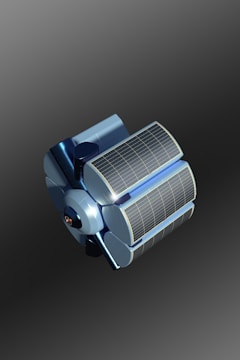 A futuristic, metallic blue satellite with large solar panels sits against a gradient background. The design is sleek and modern, with curved surfaces and detailed panel lines.