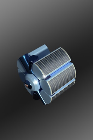 A futuristic, metallic blue satellite with large solar panels sits against a gradient background. The design is sleek and modern, with curved surfaces and detailed panel lines.