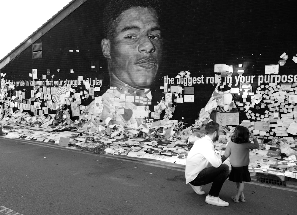 a woman kneeling down next to a wall covered in pictures