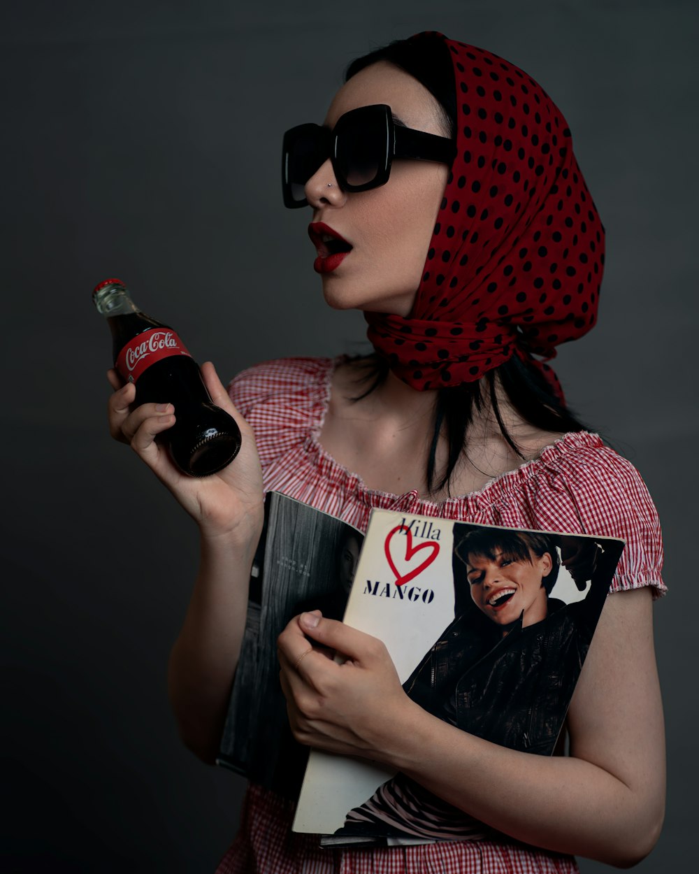 a woman in a red dress holding a book and a bottle