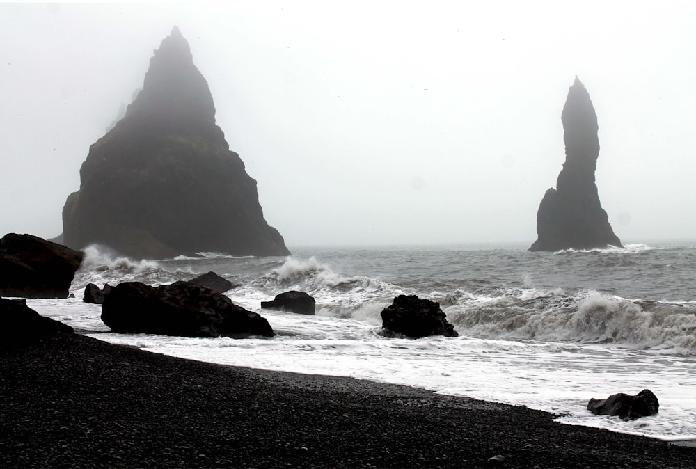 a black and white photo of the ocean and rocks