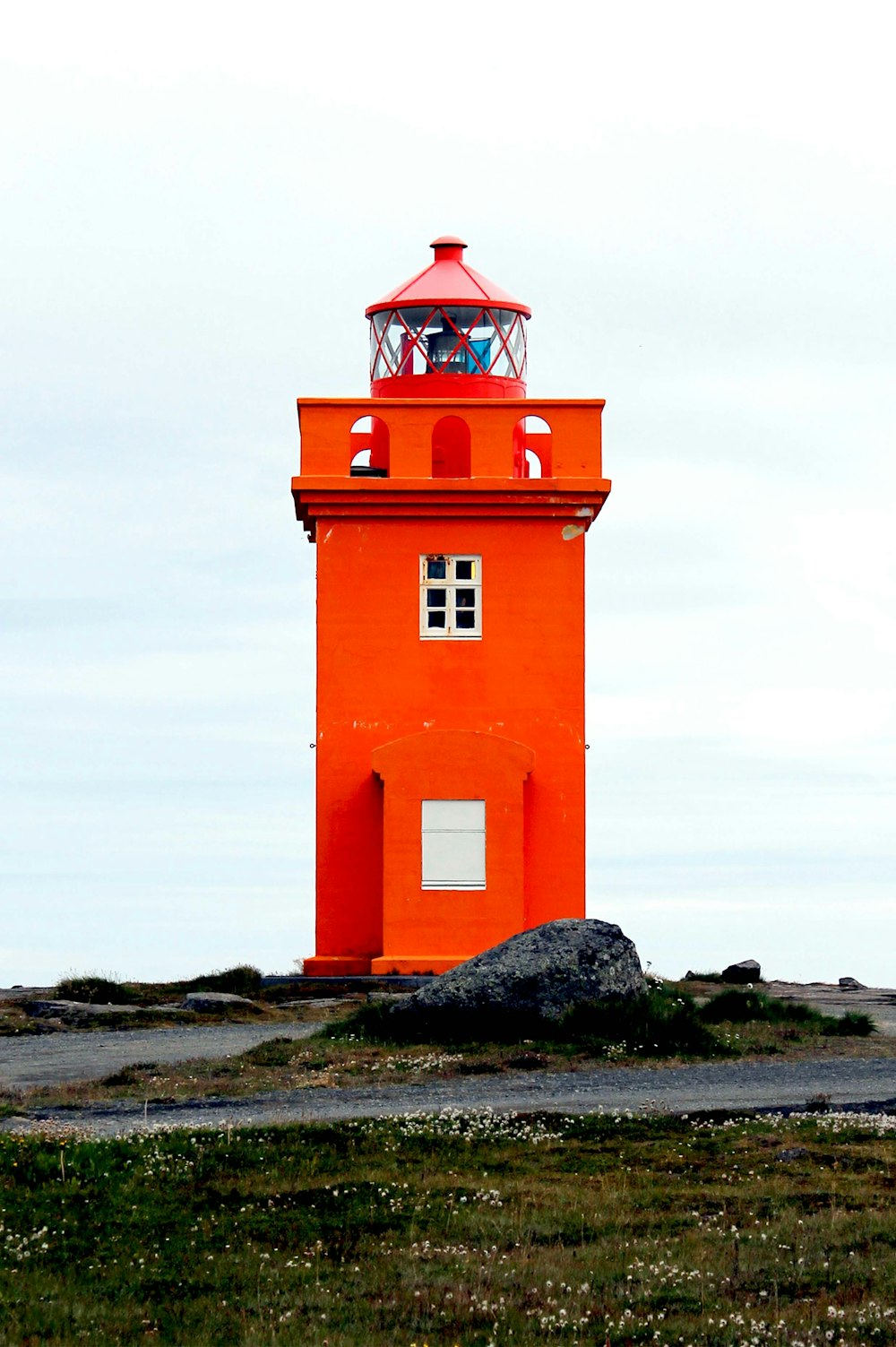 a red light house sitting on top of a hill