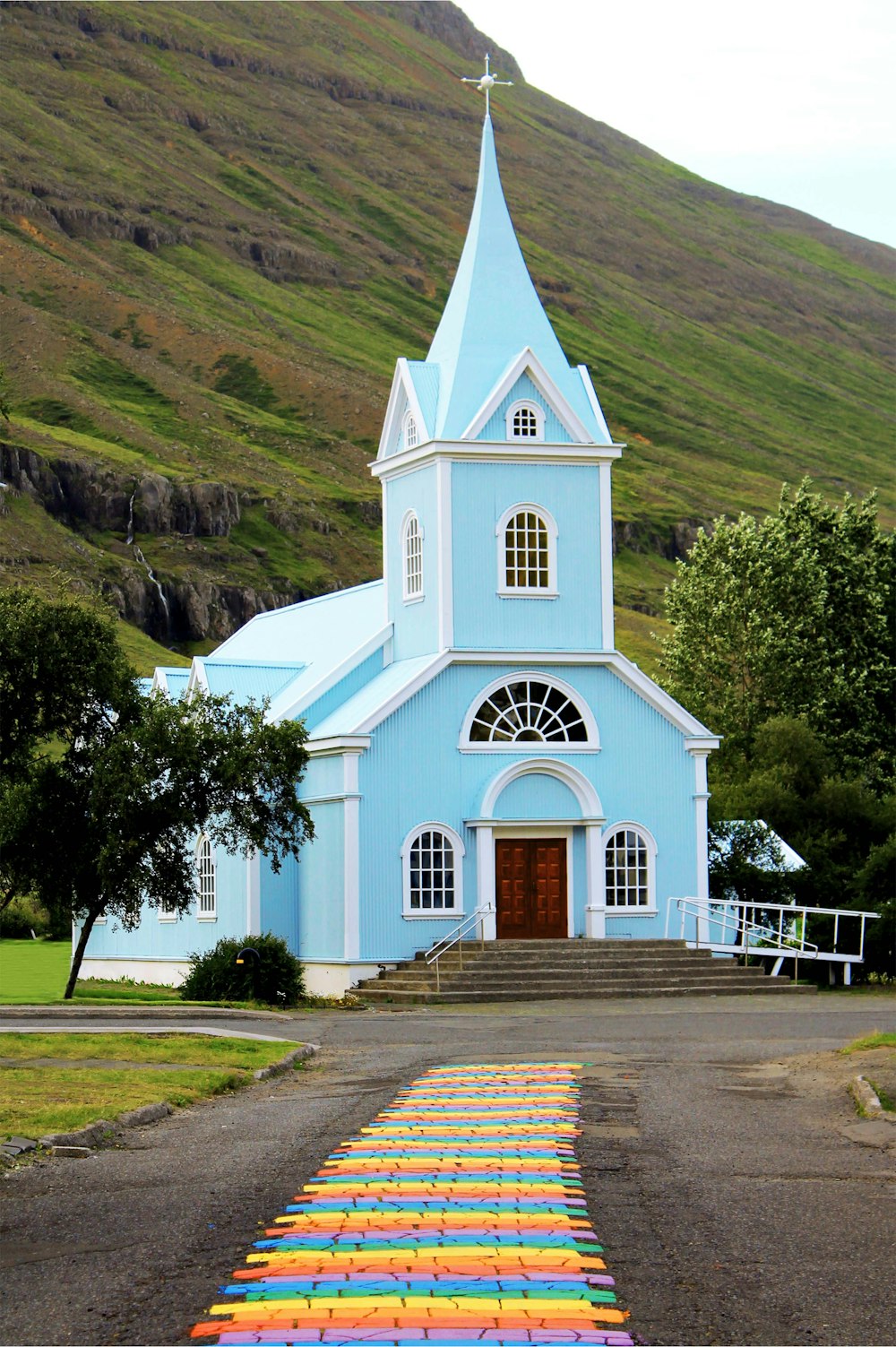 a small blue church with a steeple on a hill