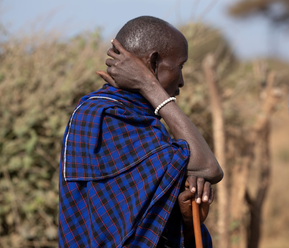 a man with a cane standing in front of a bush