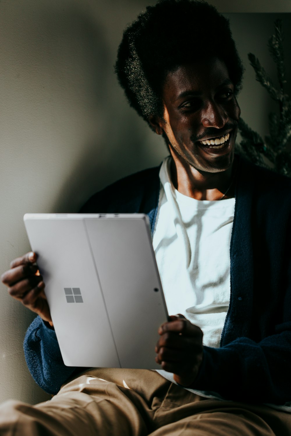 a man sitting on a bed holding a laptop computer