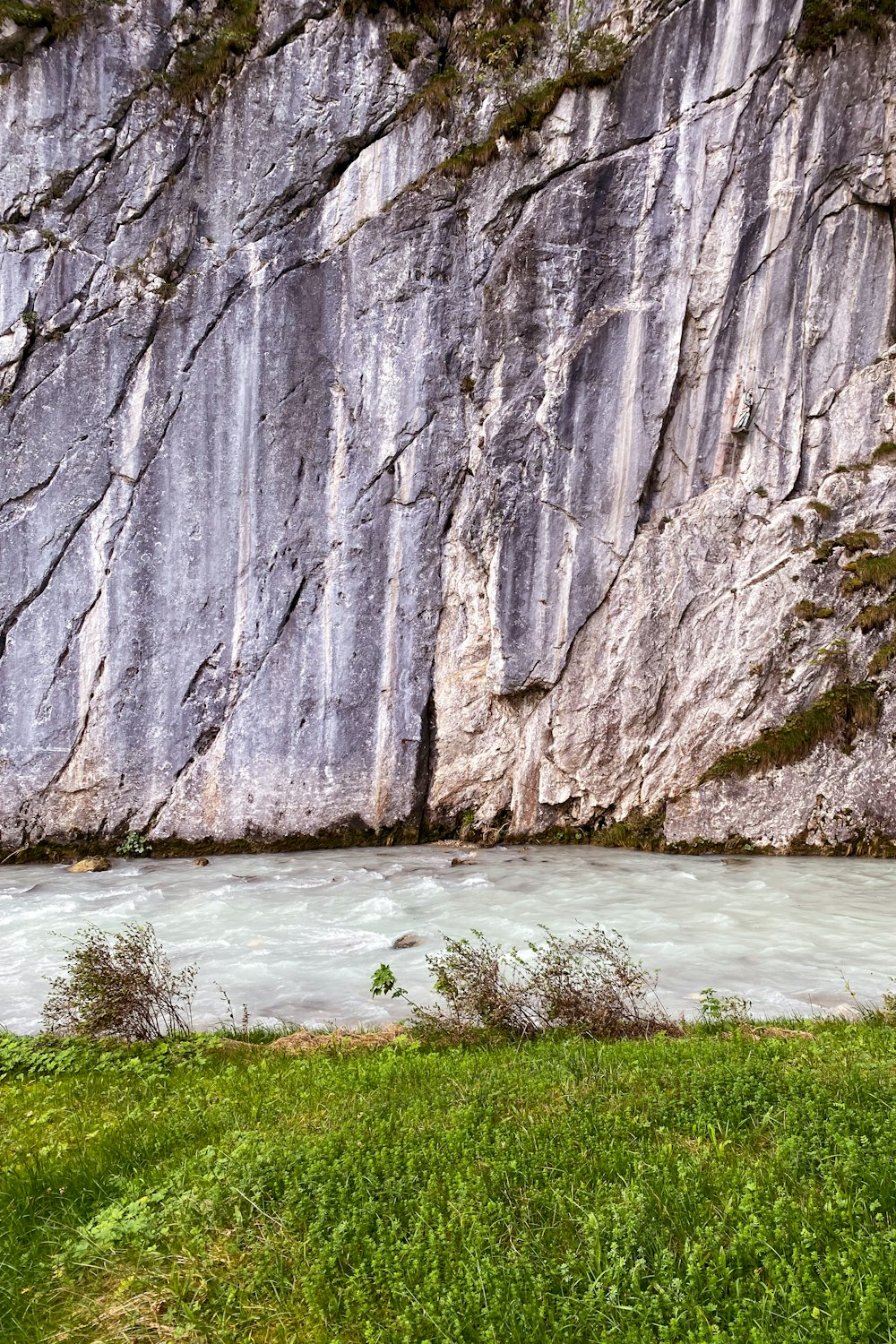 a river flowing between two large rocks next to a lush green field