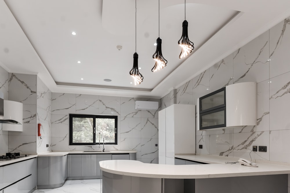 uma cozinha com uma bancada de mármore e armários brancos