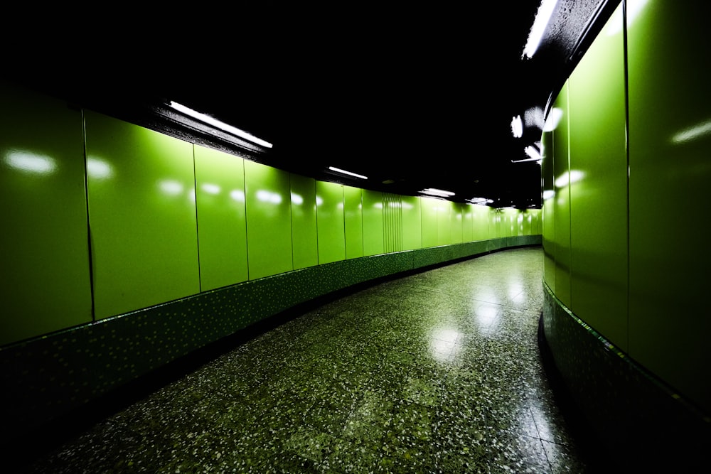 a long hallway with green walls and a black floor