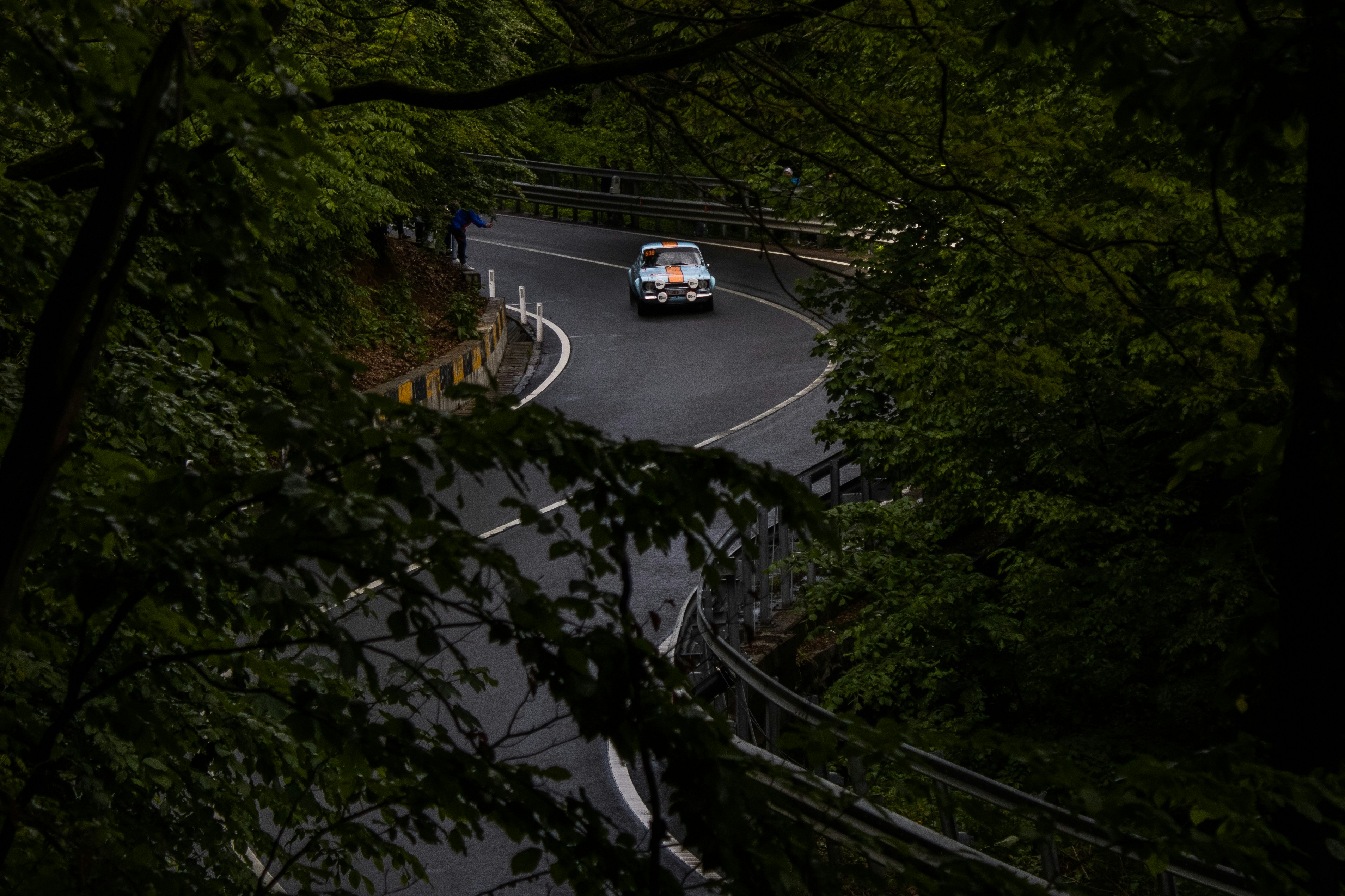 a car driving down a road surrounded by trees