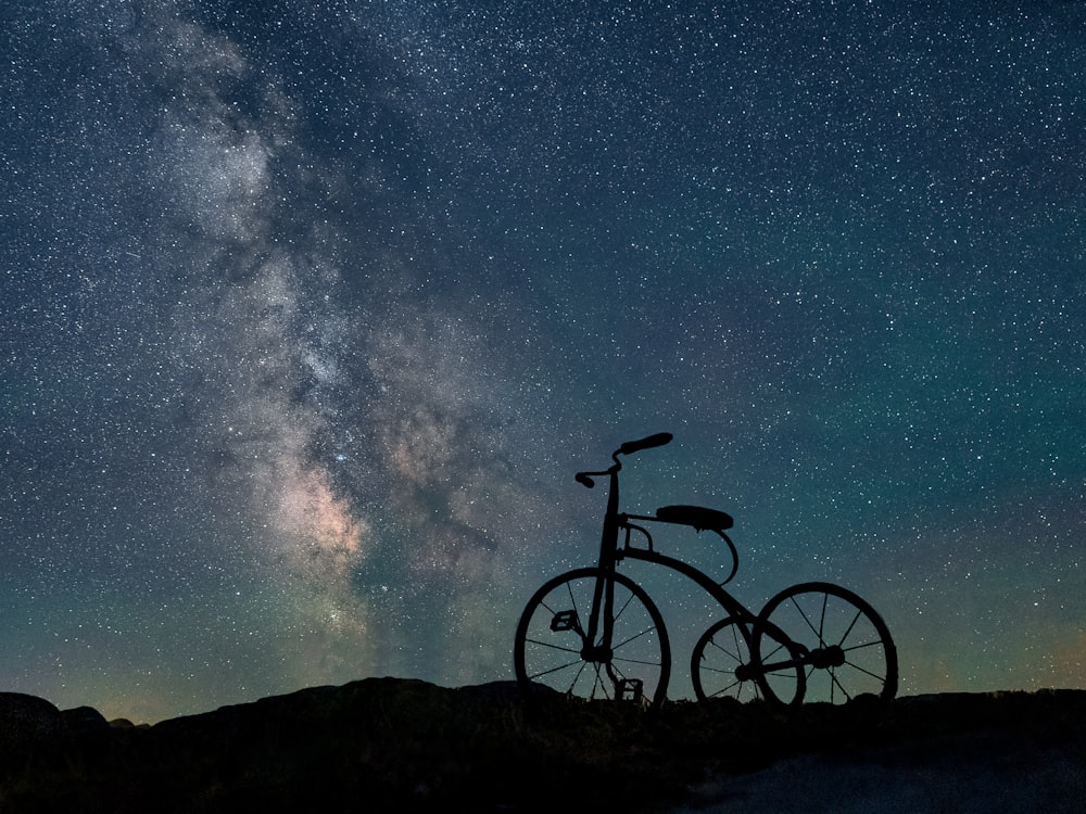 a bike parked on top of a hill under a night sky filled with stars