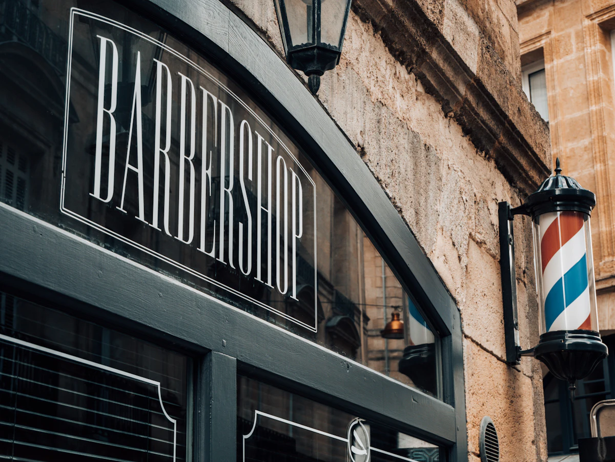 Brick storefront with a barber shop sign and pole on the sidewalk
