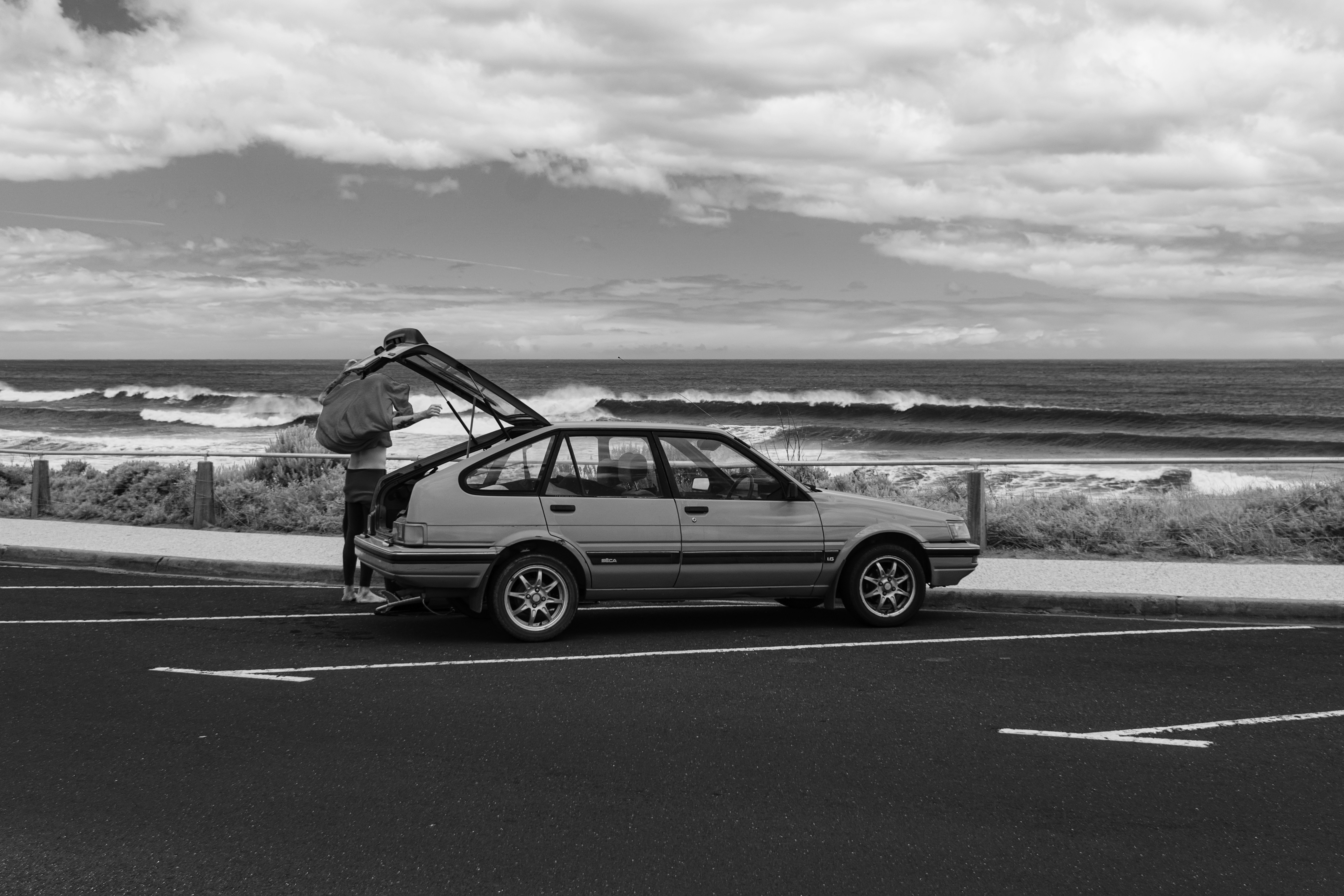 a man standing next to a car in a parking lot