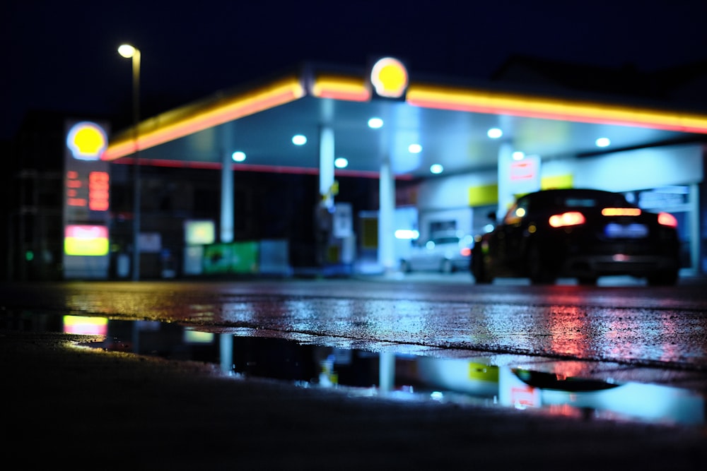 Un coche aparcado frente a una gasolinera por la noche