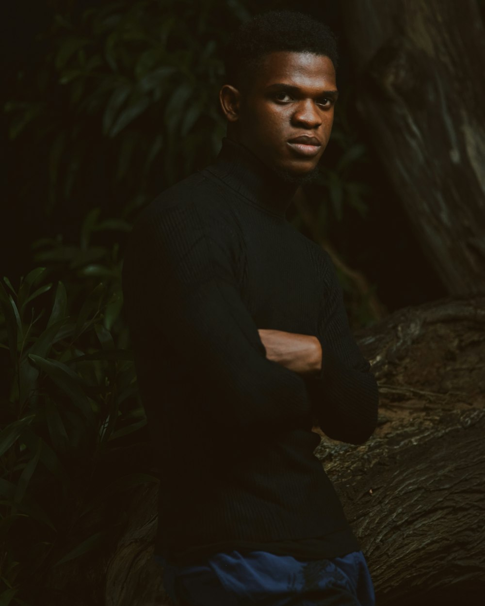 a man sitting in front of a tree with his arms crossed