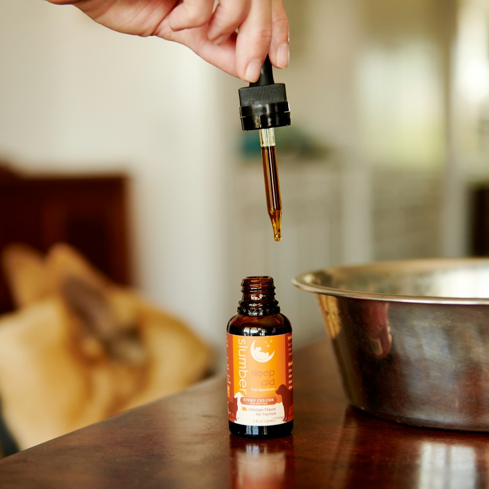 a bottle of essential oil being poured into a metal bowl