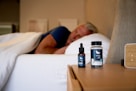 a man sleeping on a bed next to a bottle of cb