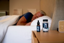 a man sleeping on a bed next to a bottle of cb