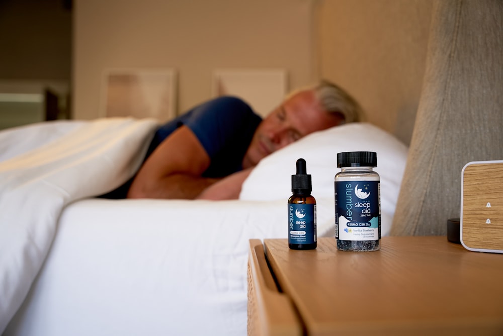 Un hombre durmiendo en una cama junto a una botella de CB