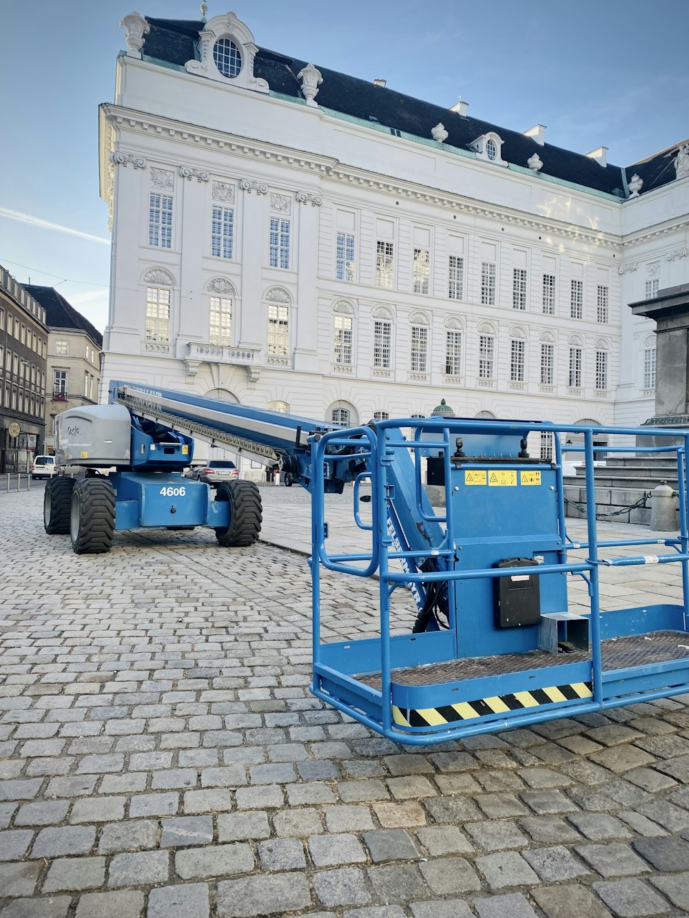 Ein großer blauer Kran sitzt vor einem weißen Gebäude