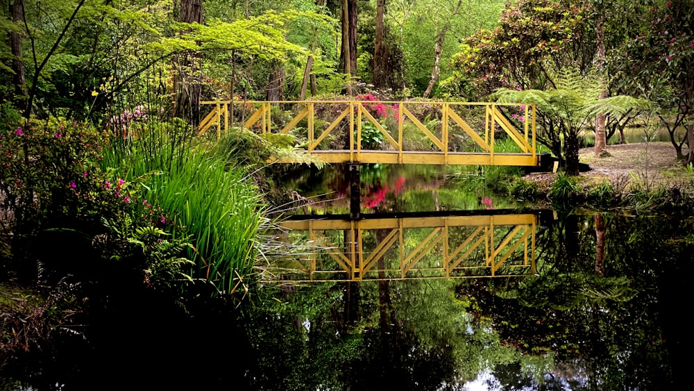 a yellow bridge over a river surrounded by trees