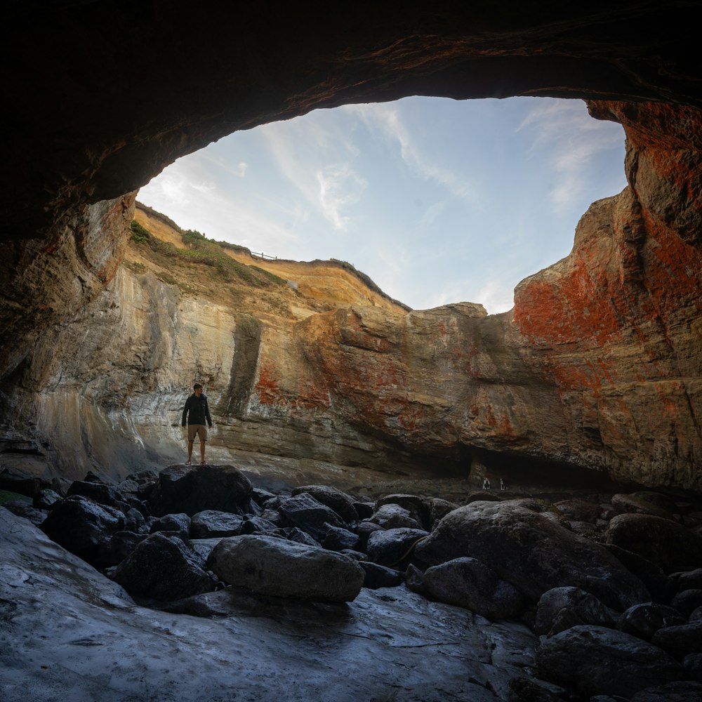 a person standing in a cave with a sky background